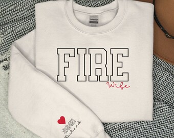 May include: A white sweatshirt with the word "FIRE" in black outlined letters and the word "Wife" in red cursive writing. The left sleeve has a red heart with the text "#2451" and "firewife" in black.