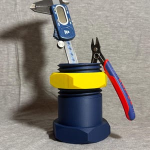 May include: A navy blue, yellow, and black 3D-printed bolt with a digital caliper and wire cutters. The caliper is blue with a digital display. The wire cutters have red and blue handles.