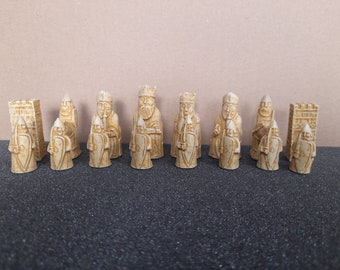 Puede incluir: Un conjunto de 12 piezas de ajedrez de cerámica beige. Las piezas son de estilo caballeros medievales e incluyen un rey, una reina, un alfil, un caballo, una torre y un peón.
