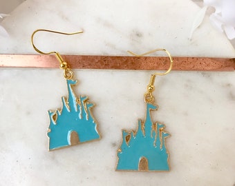 May include: A pair of gold-tone earrings featuring a blue enamel silhouette of a castle with a gold-tone flag on top.