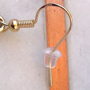 May include: Gold earring with a spring clasp and a clear plastic stopper. The earring is marked with the number "925".