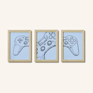 Könnte beinhalten: Ein Set aus drei gerahmten Wandbildern mit einer schwarz-weißen Strichzeichnung eines Videospiel-Controllers, die auf drei hellblaue Hintergründe aufgeteilt ist. Jedes Bild befindet sich in einem hellen Holzrahmen mit schlichtem Design.