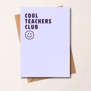 Puede incluir: Una tarjeta de felicitación rectangular de color morado claro con el texto COOL TEACHERS CLUB en morado oscuro y un icono de cara sonriente simple en morado oscuro impreso en el frente, sobre un sobre de papel marrón.