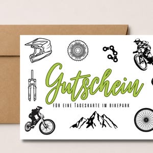 Könnte beinhalten: Eine weiße, rechteckige Gutscheinkarte mit braunem Umschlag, verziert mit schwarzen Strichzeichnungen eines Mountainbike-Helms, Zahnkranz, Kette, Federgabel, Sattel, Rad und Bergmassiv. Der Text lautet Gutschein für eine Tageskarte im Bikepark.