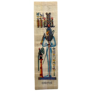 Puede incluir: Un rollo de papiro egipcio colorido que representa al dios Osiris de pie con un bastón y un símbolo ankh. El rollo está decorado con jeroglíficos y la palabra "OSIRIS" está impresa en la parte inferior.