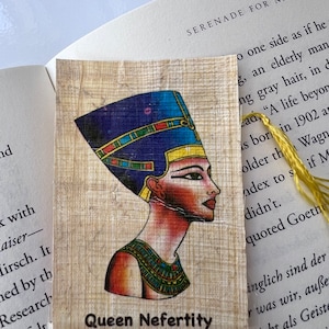 May include: A bookmark featuring a colourful illustration of Queen Nefertiti, an Egyptian queen, with a blue and gold headdress. The bookmark also includes a hieroglyphic alphabet chart.
