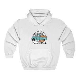 Puede incluir: Sudadera blanca con un camión azul que lleva calabazas y el texto "Take me to the Pumpkin Patch".
