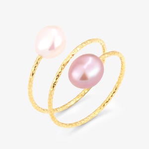 May include: A gold ring with two pink pearls. The ring is made of two bands that are twisted together. The pearls are different sizes and are set in the bands.