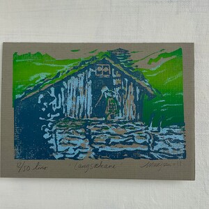 Linocut greeting card with traditional norwegian cabin and woman. Signed and numbered, in colors green blue and lightblue, framed
