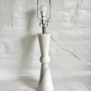 May include: A white marble table lamp with a chrome lamp holder and a white LED light bulb. The lamp has a unique hourglass shape with a gray marble vein. The lamp is approximately 15 inches tall.