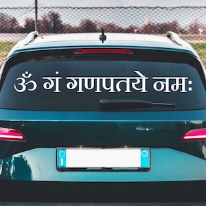 May include: A green car with a white sticker on the back window that says "ॐ गं गणपतये नमः".