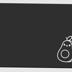 May include: A black rectangular mousepad with rounded corners. A white outline of a smiling avocado with a leaf is in the lower right corner. The mousepad is a solid black color.