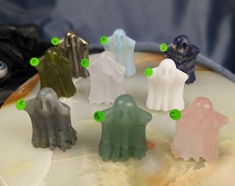 May include: Nine carved ghost figurines made of various types of stone, including green, gray, white, blue, and pink. The ghosts are all standing on a white marble surface.
