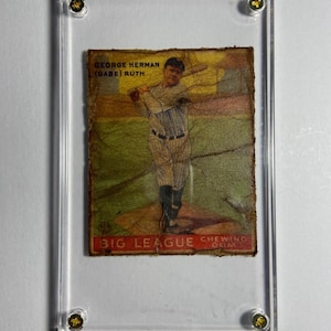 May include: A vintage baseball card featuring a color illustration of George Herman "Babe" Ruth in a baseball uniform, holding a bat and facing the viewer. The card is yellowed with age and has the text "George Herman (Babe) Ruth" and "Big League Chewing Gum" printed on it.