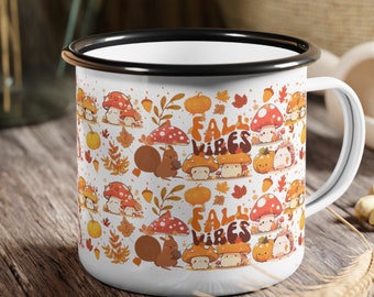May include: White enamel mug with a black rim and handle. The mug features a repeating pattern of cartoon squirrels, mushrooms, and leaves. The text "Fall Vibes" is repeated on the mug.