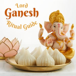 Könnte beinhalten: Eine weiße Keramikstatue von Lord Ganesha, einer hinduistischen Gottheit, die mit seinen Händen in einer Mudra-Geste sitzt. Die Statue ist mit goldenen Akzenten verziert und von einem Teller mit weißen, runden, süßen Knödeln namens Modaks umgeben. Der Text "Lord Ganesh Ritual Guide" ist in orangefarbenen und braunen Buchstaben oben im Bild geschrieben.