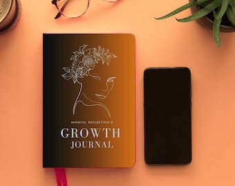 May include: A black and orange journal with a pink ribbon bookmark. The cover features a line drawing of a woman with a flower crown and the text "Mindful Reflection & Growth Journal".