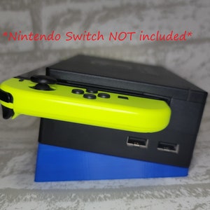May include: A black Nintendo Switch dock with a blue stand and a bright yellow Joy-Con controller attached. The text *Nintendo Switch NOT included* is visible in the image.