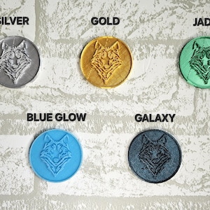 Puede incluir: Seis posavasos redondos de color plateado, dorado, jade, azul brillante y galaxia, cada uno con un dise&ntilde;o de cabeza de lobo.