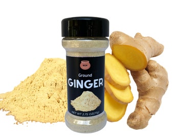 May include: A glass jar of ground ginger spice with a black label that reads "Ground Ginger" and "Nok Spice". The jar is sitting on a pile of ground ginger spice. There are also fresh ginger roots in the image.