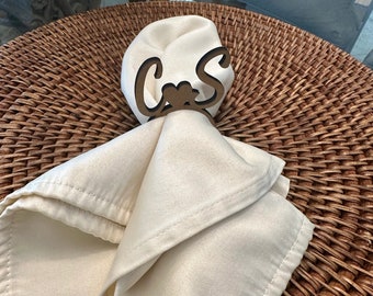 May include: A white napkin with a wooden napkin ring that says "C & S" in cursive. The napkin ring has a small heart in the centre.