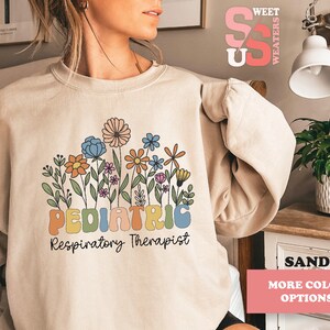 May include: A beige sweatshirt with a floral design and the text "PEDIATRIC Respiratory Therapist".