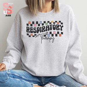a woman wearing a grey sweatshirt with the words respiratory on it