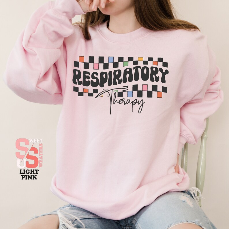 a woman sitting on a chair wearing a pink sweatshirt
