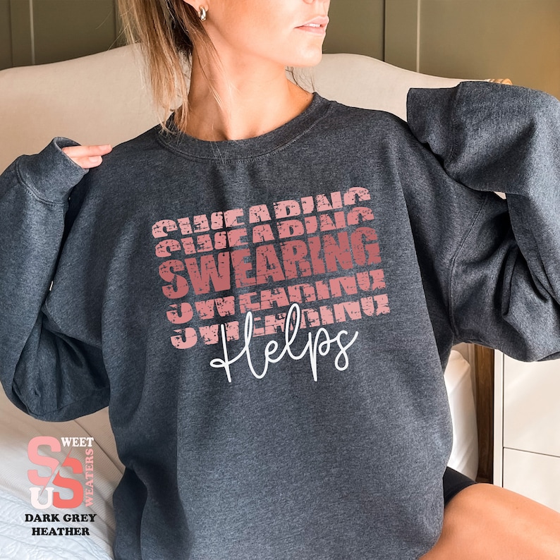 a woman sitting on a bed wearing a sweatshirt