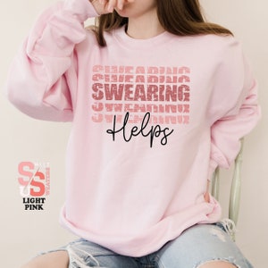a girl wearing a pink sweatshirt and ripped jeans