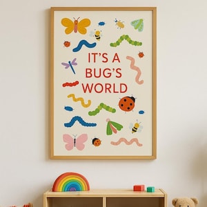 以下が含まれることがあります： 明るいベージュの背景に、昆虫のカラフルなイラストと赤い文字で「IT'S A BUG'S WORLD」と書かれた額入りのプリント。 アートワークには、蝶、蜂、てんとう虫、イモムシが含まれています。 木製の虹と他のおもちゃが下の棚にあります。