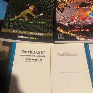 May include: Four technical books including Linux Forensics with Python and Shell Scripting by Dr. Philip Polstra, Graphics Gems III edited by David Kirk, a DarkBASIC Programming Language User Manual, and a Dark BASIC Professional Programming Manual.