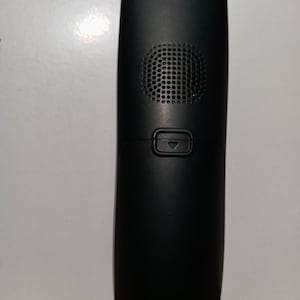 May include: A black cordless phone handset with a speaker grille and a button with a downward arrow.