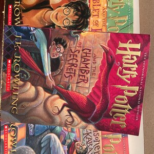 May include: A stack of three Harry Potter books by J.K. Rowling. The covers feature illustrations of characters and scenes from the series. Titles include "Goblet of Fire", "Chamber of Secrets", and "Prisoner of Azkaban".