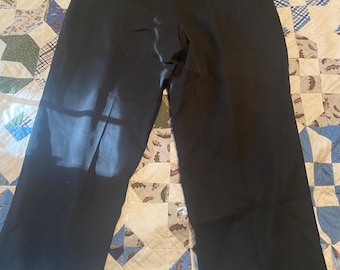 May include: Black dress pants with a wide leg design. The pants have a classic, tailored look with a button and zipper closure. The fabric appears to be a smooth, solid color, suitable for formal or business attire.