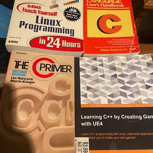 May include: Four programming books including Sams Teach Yourself Linux Programming in 24 Hours, C Language User's Handbook, The C Primer Second Edition, and Learning C++ by Creating Games with UE4, featuring various titles and technical text.