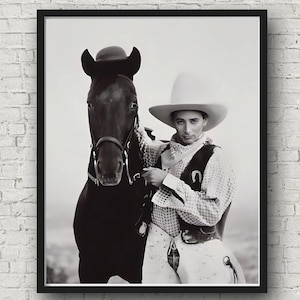 Può includere: Stampa incorniciata in bianco e nero di una persona in abiti da cowboy con un cavallo. La persona indossa un cappello a tesa larga, un gilet e una camicia fantasia. Il cavallo è scuro con una briglia.