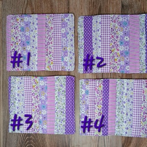 May include: Four rectangular, quilted placemats with a patchwork design. Each mat features a mix of floral, striped, and polka dot fabrics in shades of purple and white. The numbers #1, #2, #3, and #4 are written in purple on each mat.