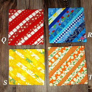 May include: Four square fabric coasters with diagonal stripes. The coasters feature various patterns, including red and white stripes, blue floral, yellow daisy, and orange floral designs. Each coaster is approximately 4 inches square.