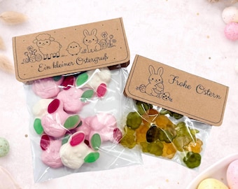 May include: Two clear cellophane bags filled with Easter-themed candies. One bag contains pink and white bunny-shaped candies with green and red accents. The other bag has green and yellow gummy candies. Each bag has a brown paper topper with Easter-themed illustrations and text.