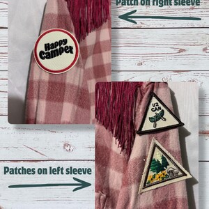 On the top of the right sleeve there is a patch that says "Happy Camper" on it and on the other sleeve are 2 up-cycled scout patches that are camping themed.