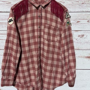 The front of this flannel shirt has fringe on both shoulders.