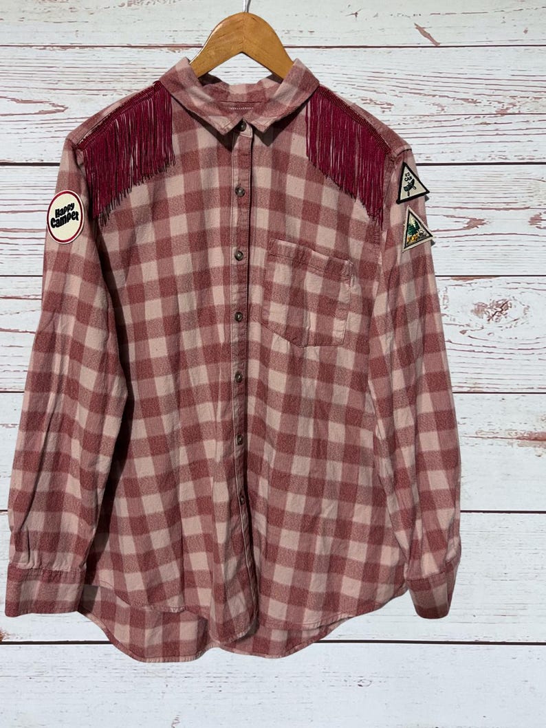 The front of this flannel shirt has fringe on both shoulders.