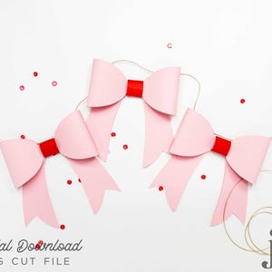 May include: Three pink paper bows with red centers, tied with gold string, on a white background. The bows are arranged in a triangular shape.