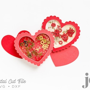 Puede incluir: Dos tarjetas de corte rojo en forma de corazón con bordes festoneados. Cada tarjeta tiene una ventana transparente que revela brillo dorado y confeti rojo en el interior. El texto "Digital Cut File SVG . DXF" está en la parte inferior de la imagen.