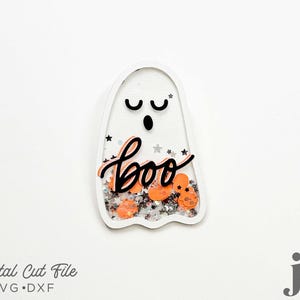 May include: A white ghost-shaped cutout with a black "boo" and orange and silver glitter inside.