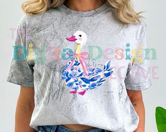 May include: A gray t-shirt with a white duck wearing a pink bow and blue floral pattern. The duck is standing on a gray background.