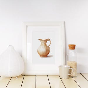 May include: A watercolor painting of a brown ceramic pitcher with a handle, framed in a white frame. The painting is displayed on a white shelf with a white diffuser and a glass jar with a cork lid.