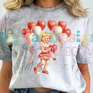 Könnte beinhalten: Ein graues T-Shirt mit einem Used-Look, das eine Vintage-Illustration eines jungen Mädchens zeigt, das einen herzförmigen Ballon hält. Das Mädchen trägt ein rosa Kleid und ist von roten und weißen herzförmigen Ballons umgeben.