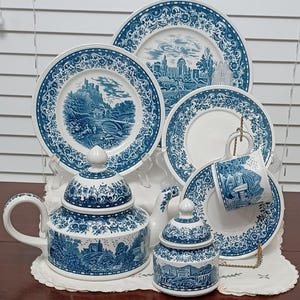 May include: A blue and white porcelain tea set with a floral design. The set includes a teapot, sugar bowl, creamer, cup and saucer, and two plates.